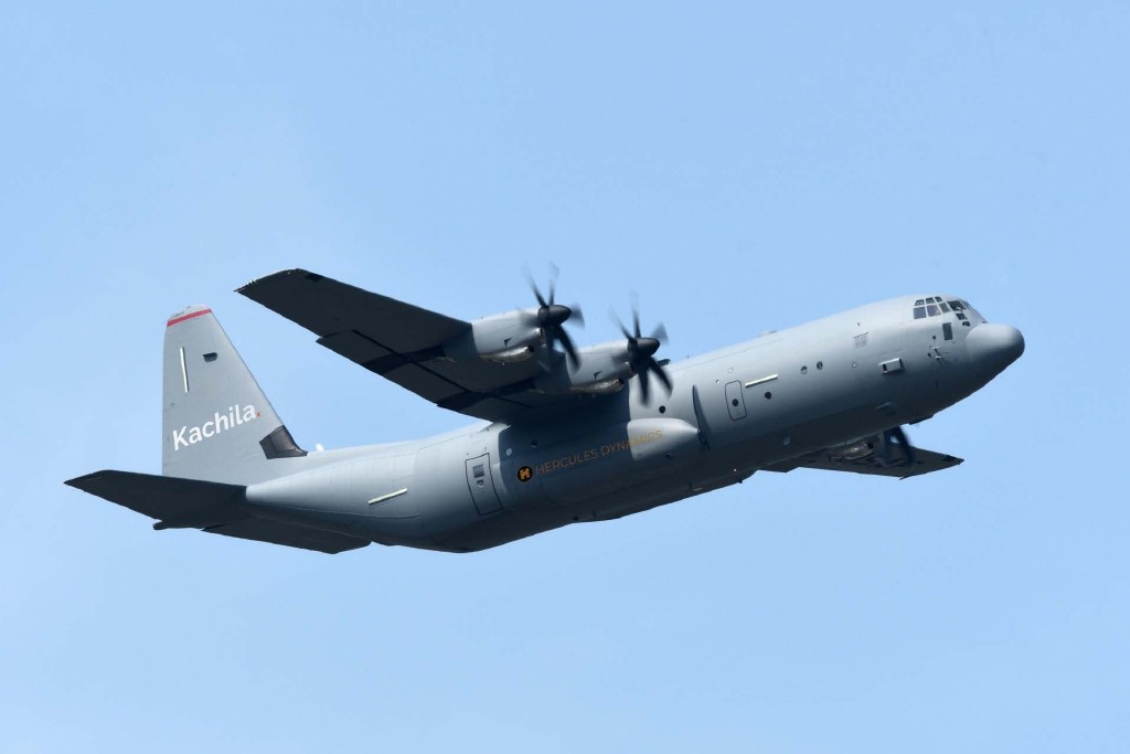 Transport aircraft in flight carrying Kachila and Hercules Dynamics branding